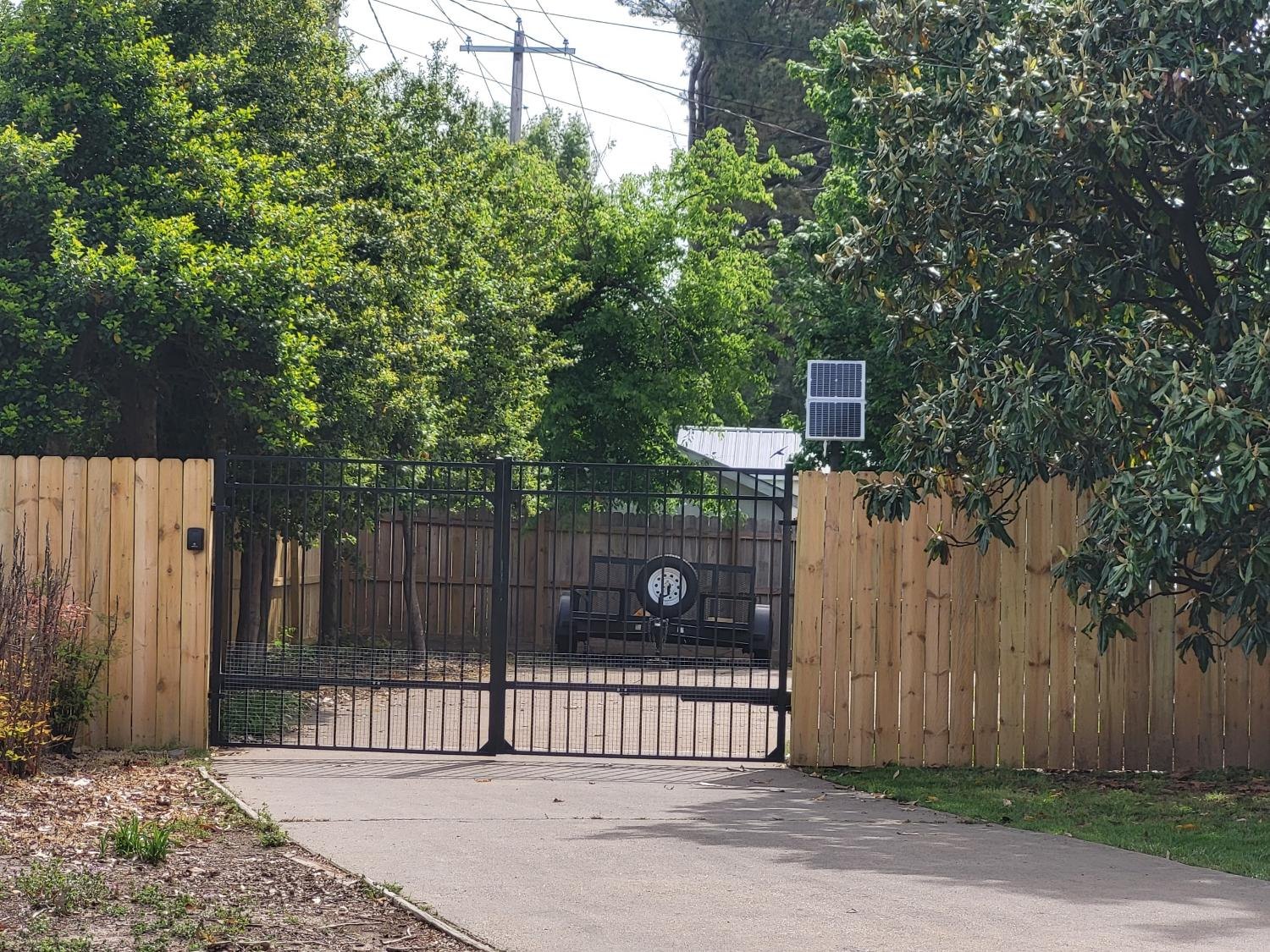 Cedar privacy fence with a black ornamental driveway gate and a solar operator.